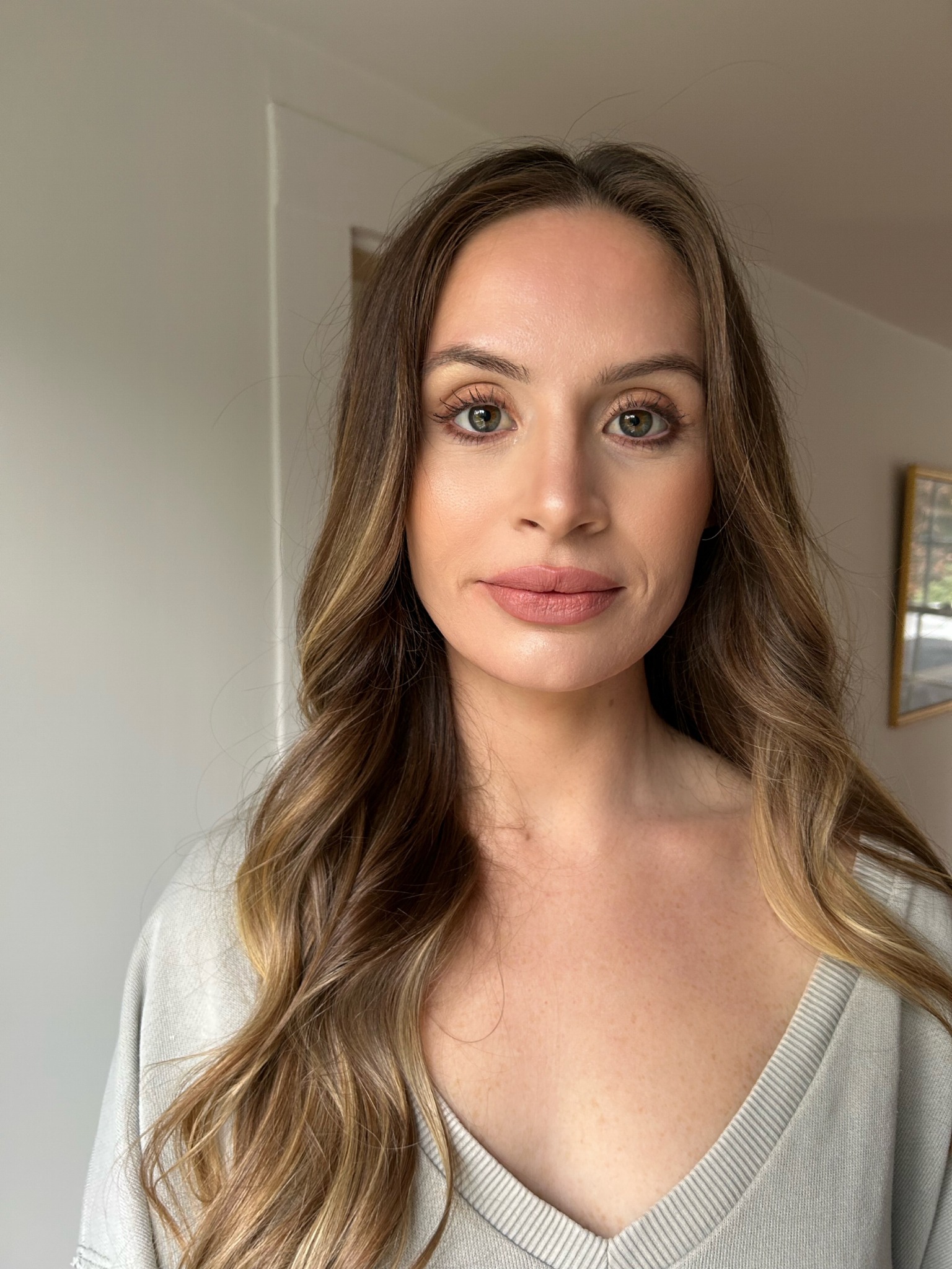 Bride putting on pearl earrings with elegant updo hairstyle by Doorbell Salon