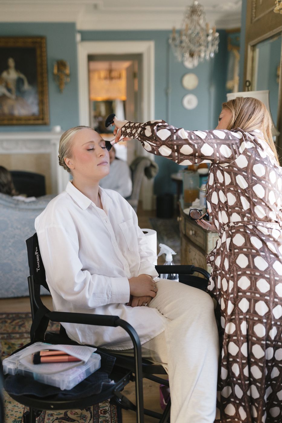 Doorbell Salon makeup artist applying makeup to a bride in a pale blue room on the wedding morning